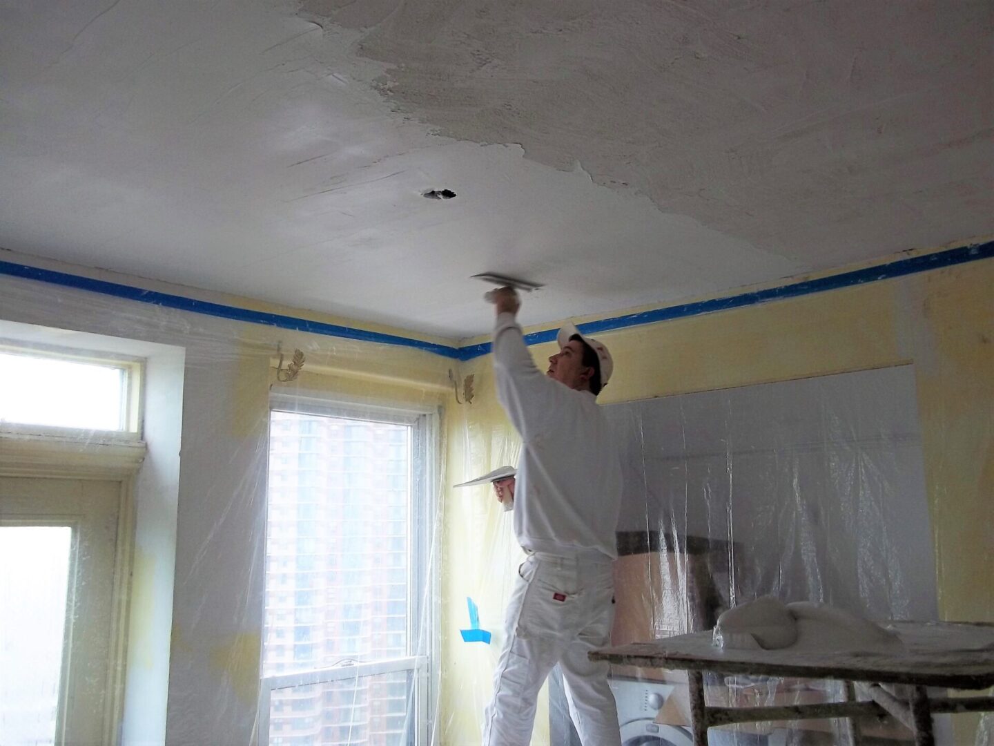 a man is applying finish coat on a ceiling